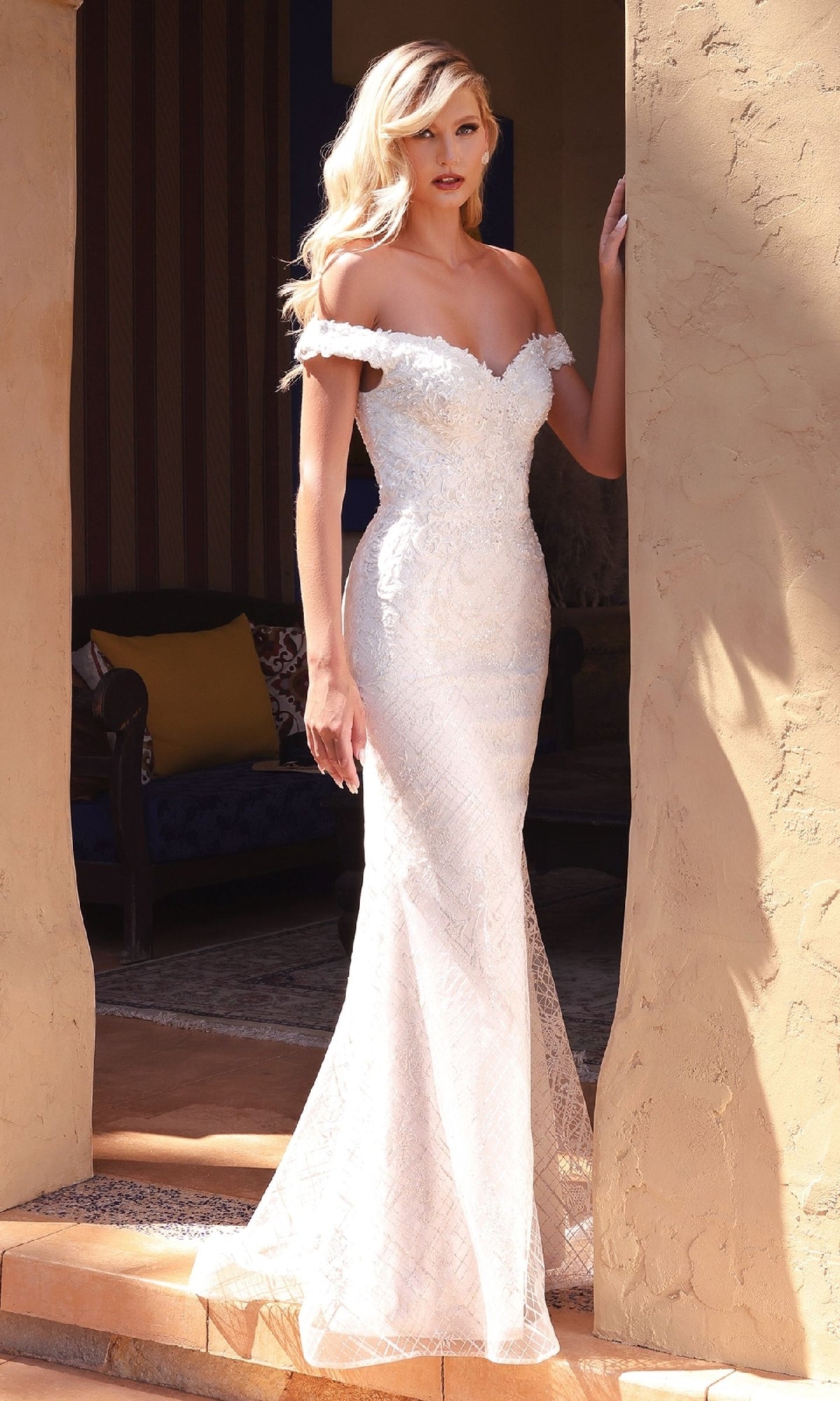 A woman wearing the Long Off-White Wedding Dress: Ladivine CD929 stands in a doorway, with a lovely tiled floor and cozy seating area visible behind her.